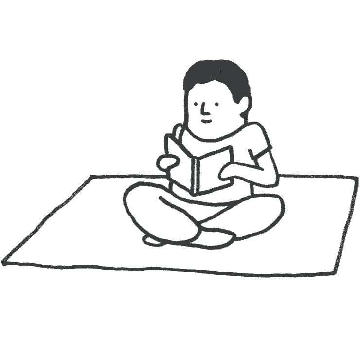 Mann sitzt auf einer Decke, liest ein Buch und atmet ruhig